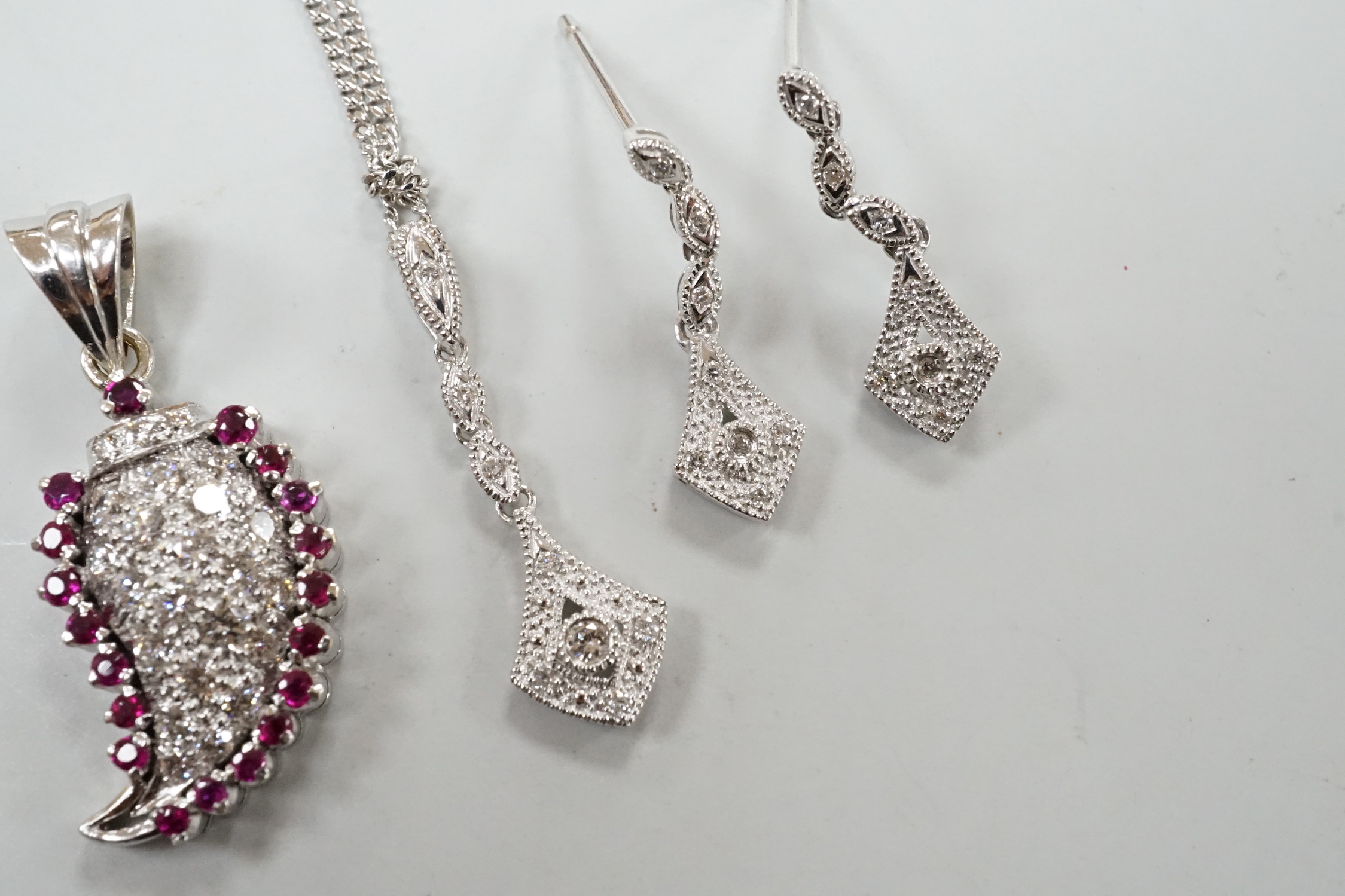 A modern white metal ruby and diamond cluster set drop pendant, modelled as a pear, overall 26mm, together with a modern 375 white metal pendant, 25mm, on a 9ct white gold chain and a pair of matching drop earrings, one